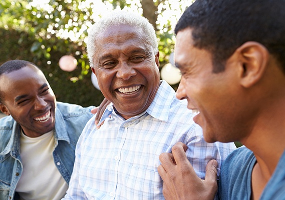 Patient in Springfield smiling confidently with family after getting dentures