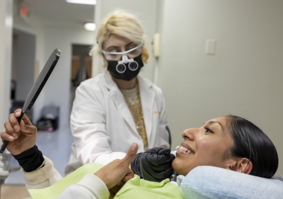 Dentist shadematching patient's smile while they check a mirror