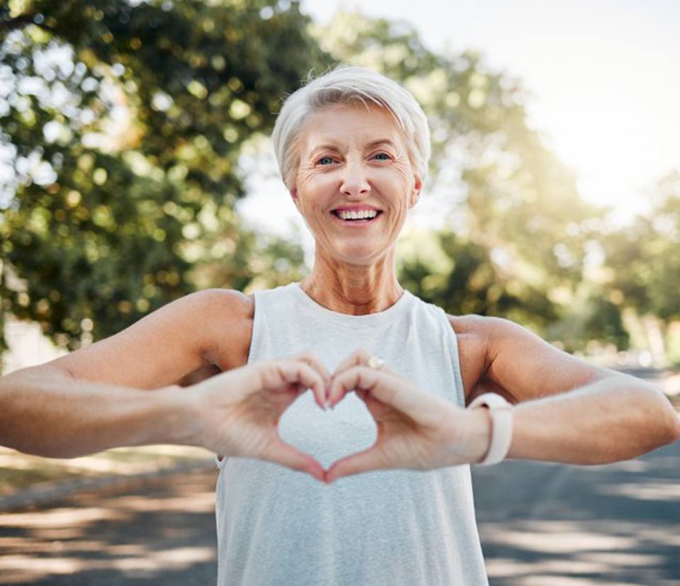 Lady smiles and makes shape of heart with hands