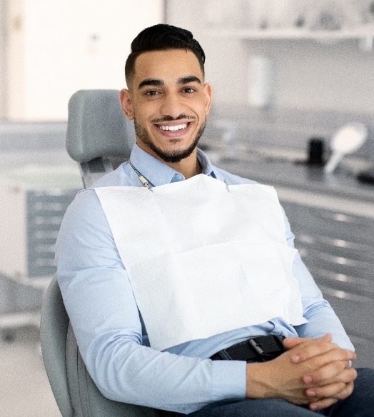 Bearded man smiling and adjusting his glasses