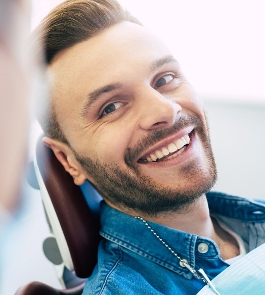 Bearded man smiling and adjusting his glasses