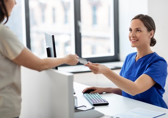 a front desk worker taking a patient’s credit card